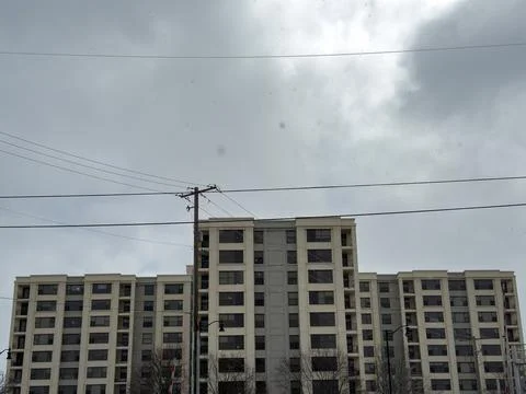 Building stands under cloudy sky with power lines visible in front during t.. Stockfoto's