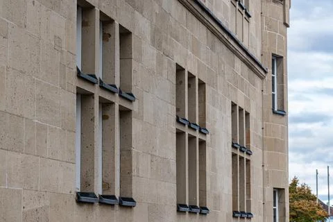 Building with stone facade and multiple windows against cloudy sky Stock Photos