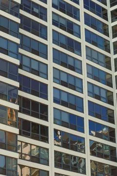 Building structure shows windows reflecting sunlight in a busy urban area. Th Stock Photos