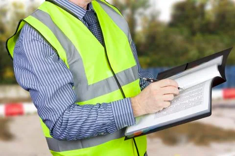 Building surveyor in high visibility checking data in site folder Stock Photos