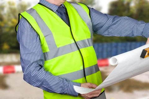 Building surveyor in high visibility checking site plans holding spirit level Stock Photos
