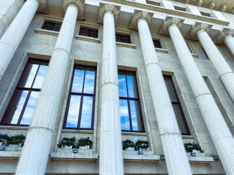 Building with tall columns and windows reflecting the sky in a city environ.. Stock Photos