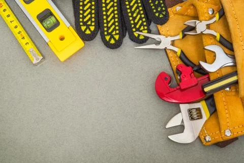 Building tools in the bag and work gloves on gray desktop are used to replace or Stock Photos