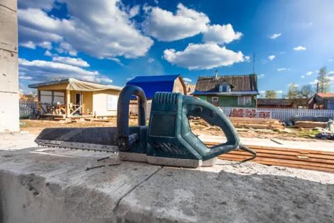 The building under construction and electric saw on the foreground in summer Stock Photos
