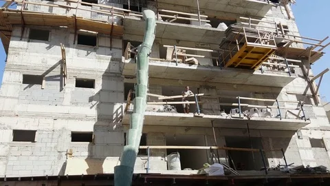 Building under construction, construction workers, waste removal sleeve, buckets Vídeos de archivo 80665373