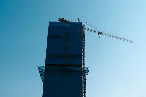 Building under construction with crane against blue sky Stock Photos