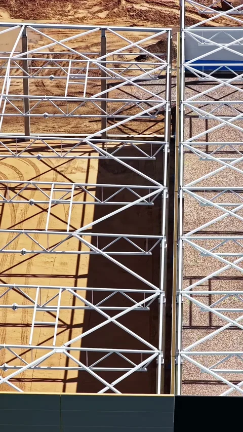 Building under construction showing steel truss roof framing from an aerial Stock Footage 342978772
