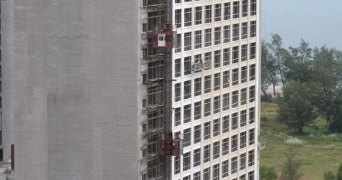 Building under construction with two elevators, workers, and unfinished facades Stock Footage 294742912