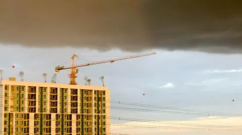 Building under construction under the rain clouds at sunset. Stock Photos