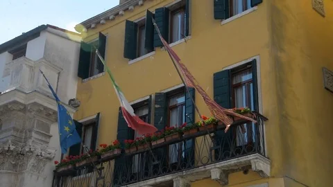 Building in Venice. On the balcony hanging flags: - city of Venice, - country of Stock Footage 76842704