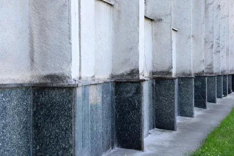 Building wall with stone base and texture near grassy area Stock Photos