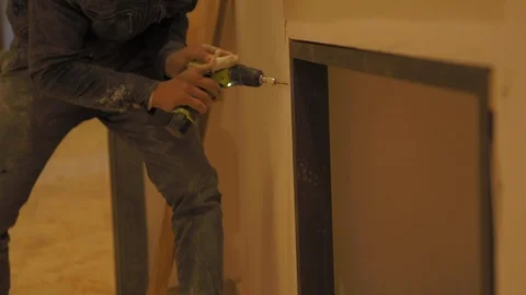 Building Worker Drilling a hole with a portable drill to fix the wooden frame of Stock-Footage 110771549