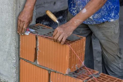 Building worker setting string line between clay block Stock Photos
