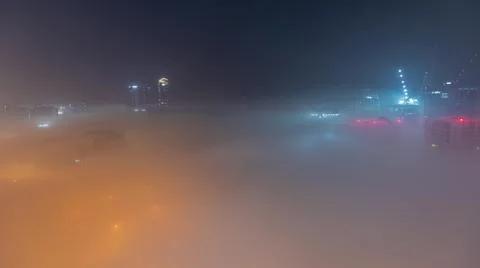 Buildings are covered in thick layer of fog in Business Bay night timelapse. Stock Photos