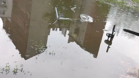 Buildings reflected in a big pool on a rainy day Stock Footage 147626880