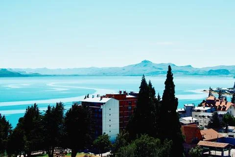 Buildings on the shore, against the backdrop of the lake and mountains Stock Photos