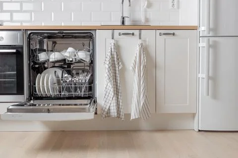 Built-in dishwasher full of clean dishes with its door open, white utensil. M Stock Photos