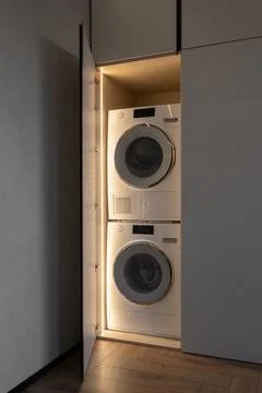 Built-in laundry cabinet with stacked white washing machine and dryer Stock Photos
