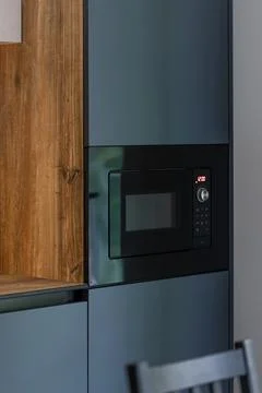 Built-in microwave in a modern kitchen. Dark cabinets with warm wood. Stock Photos