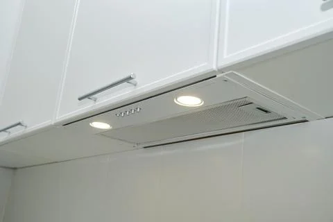 Built-in range hood under white kitchen cabinet with led light. Modern extrac Stock Photos