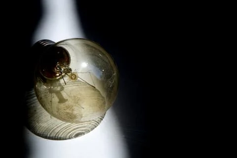 Bulb in Focus. Casting Shadows on a Dark Surface Stock Photos
