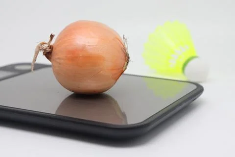 Bulb on a kitchen scale against the background of a shuttlecock. Calorie coun Stock Photos