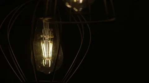 Bulb moves on a wire (naturally). Lamp swinging on a black background. Slow Vídeo Stock 72299874