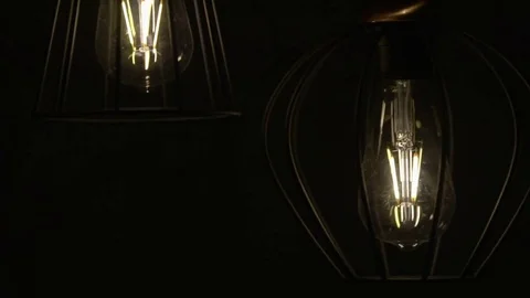 Bulb moves on a wire (naturally). Lamp swinging on a black background. Slow Vídeos de archivo 72299900