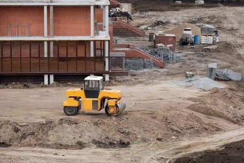 Buldozer making and constructing new asphalt road near civil building. Stock Photos