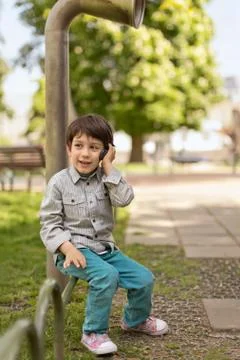 Bulgaria, Sofia, Boy (4-5) sitting on park railing talking on mobile phone Stock Photos