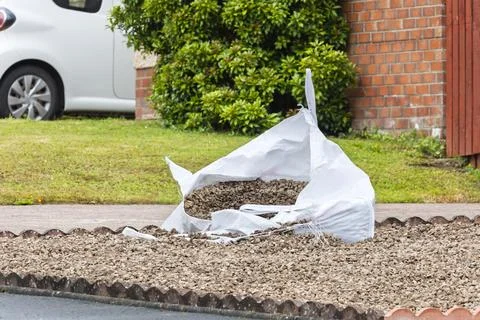 Bulk bag of gravel split open during domestic landscaping project Fotos de archivo