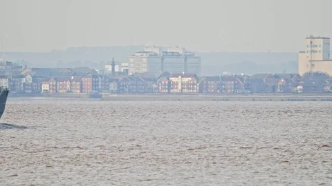 Bulk cargo Ship in traveling down estuary past city scape. Stock Footage 120350136