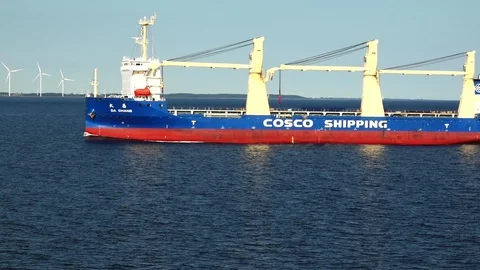 Bulk carrier with red blue side sails along high windmills Stock Footage 113093714