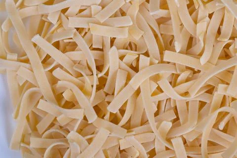 Bulk egg noodles ready for kitchen use showing large quantity ribbons, unif.. Stock Photos