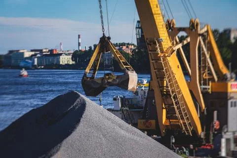 Bulk-handling crane unloading sand, road metal and gravel from cargo vessel s Stock Photos