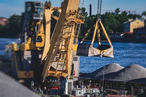 Bulk-handling crane unloading sand, road metal and gravel from cargo vessel s Stock Photos