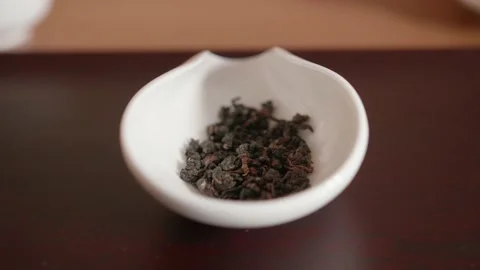 Bulk rolled tea leaves dropping in a porcelain chinese object - Gong Fu Cha Stock Footage 153417212