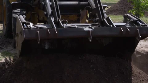 Bulldozer bucket unloading fresh topsoil for a rain garden construction project Stock Footage 342282414