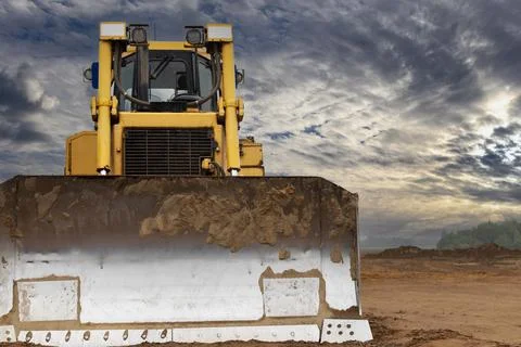 Bulldozer machine is leveling construction site. Photos