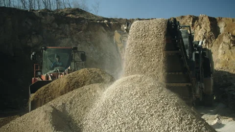 Bulldozer operator loading rock pieces, crushing machine in process, quarry work Video stock 294074250