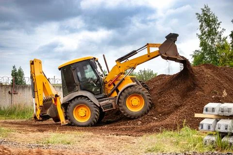 A bulldozer or a loader actively digging into a large pile of dirt at a const Photos