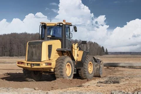Bulldozer or loader machine is leveling construction site. Photos