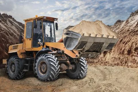 Bulldozer or loader moving sand on a construction site in a pit. An earthmovi Stockfoto's