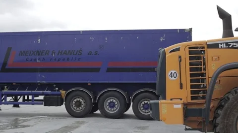 Bulldozer passes in front of camera and pours load into a trailer Stock Footage 72859062