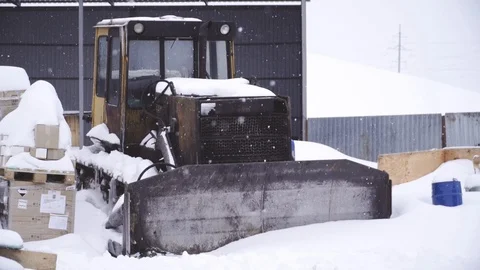 Bulldozer stands in a dump in winter and it snows Video stock 105371302