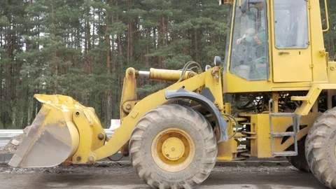 A bulldozer stands on the road. Inside, a worker sleeps at lunchtime Stock Footage 75056289