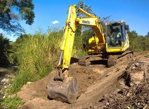 Bulldozer taking dirt off by a river. Construction site Stock Photos