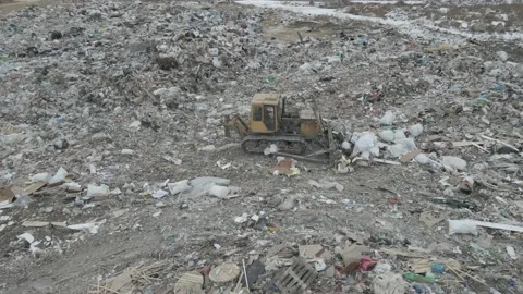 Bulldozer tractor pushes garbage from a mountain in a city dump Stock-Footage 145720942