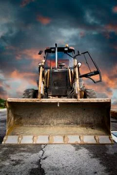 Bulldozer, yellow tractor on dramatic sky background Stock Photos