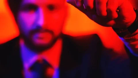 Bullet cases spill out of the hands of man. Shooting in red light Stock Footage 101547990